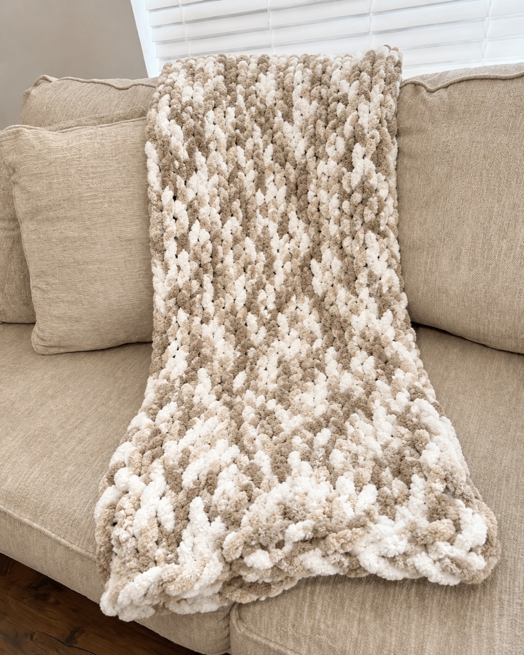 Full view of the Neutral Camo handmade chunky throw on a neutral sofa